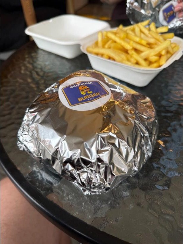 Burger Oklahoma zapakowany w folię z naklejką marki